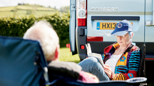 Two people relaxing outside their campervan